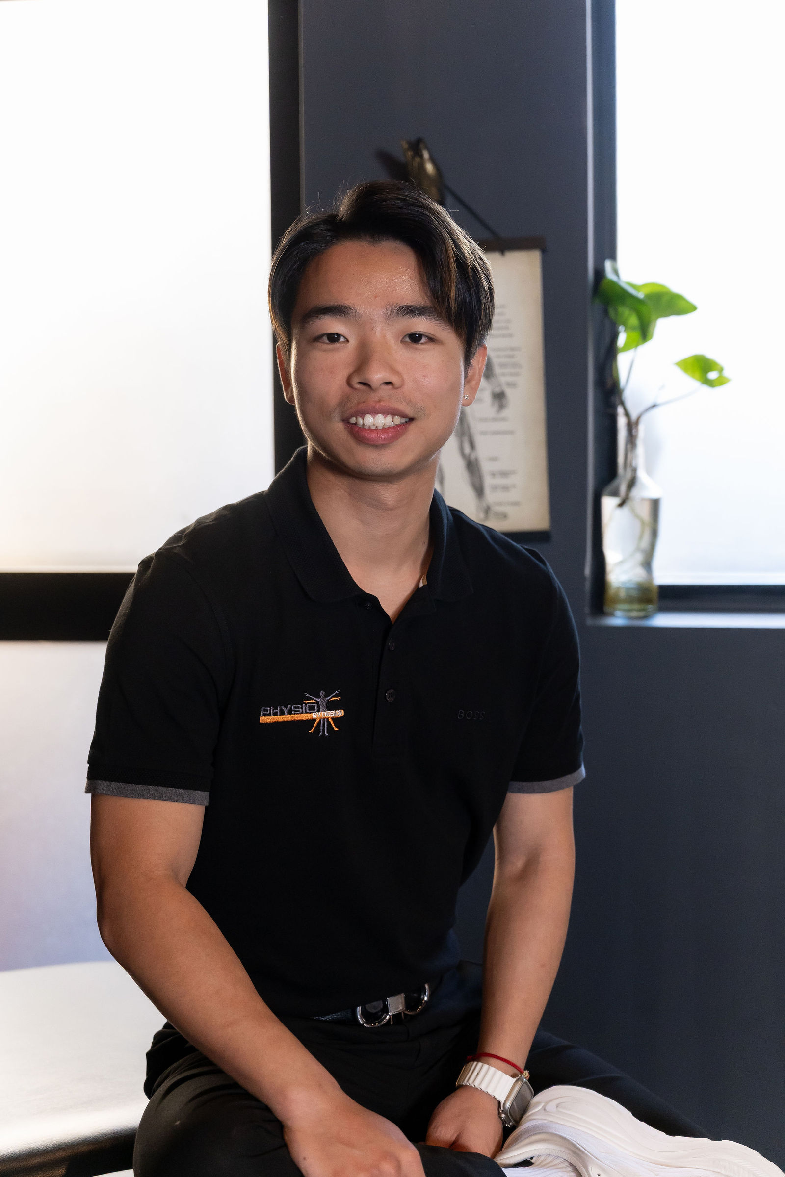 Henry, Physiotherapist at Physio by Design, smiling in his Physio by Design polo shirt